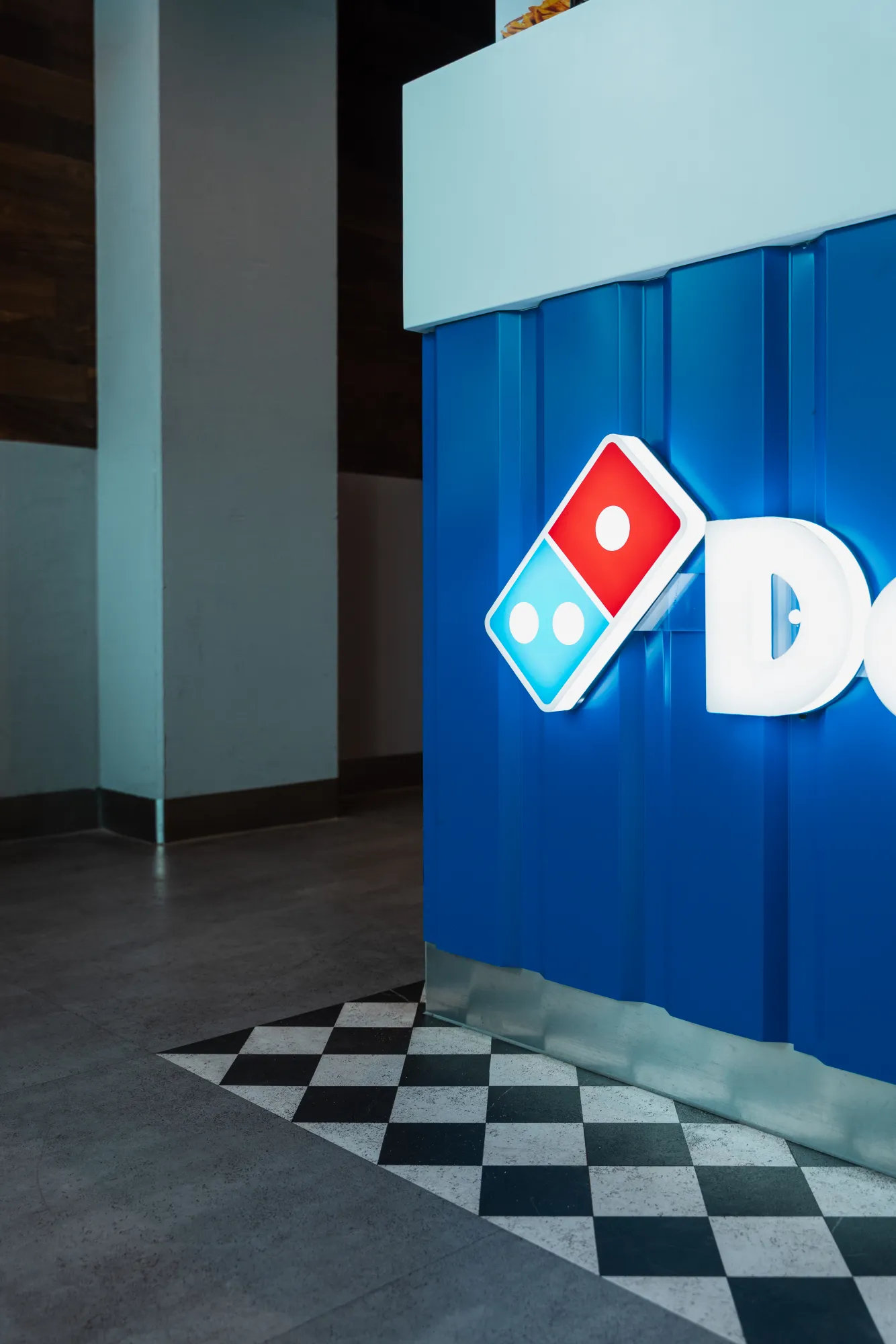 Niebieska lada z logo Domino's i posadzka w szachownicę