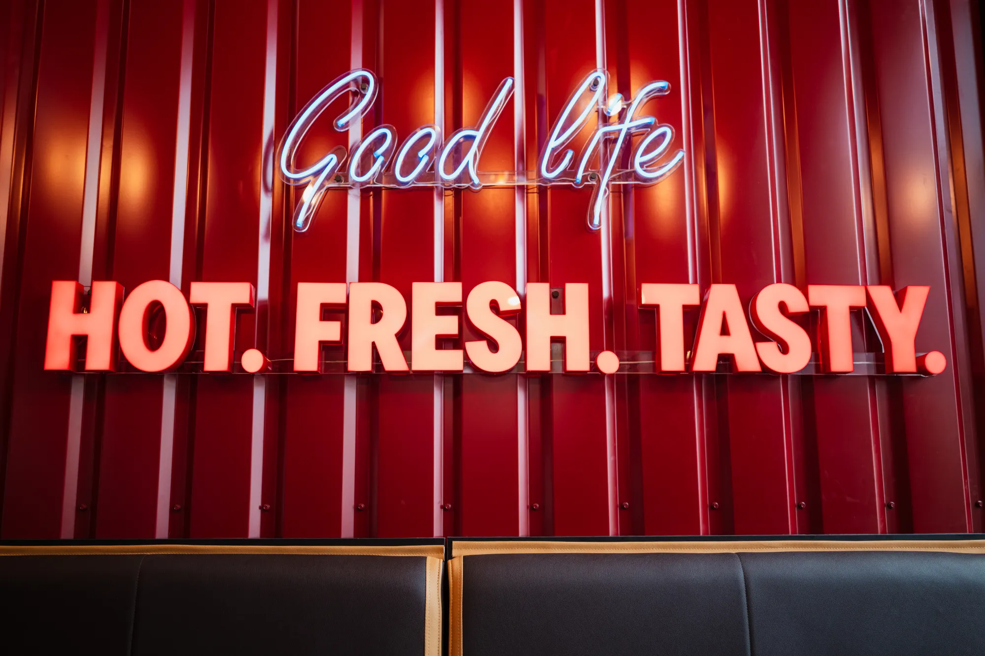 Neon „Good life. Hot. Fresh. Tasty.” na czerwonej ścianie lokalu Domino's